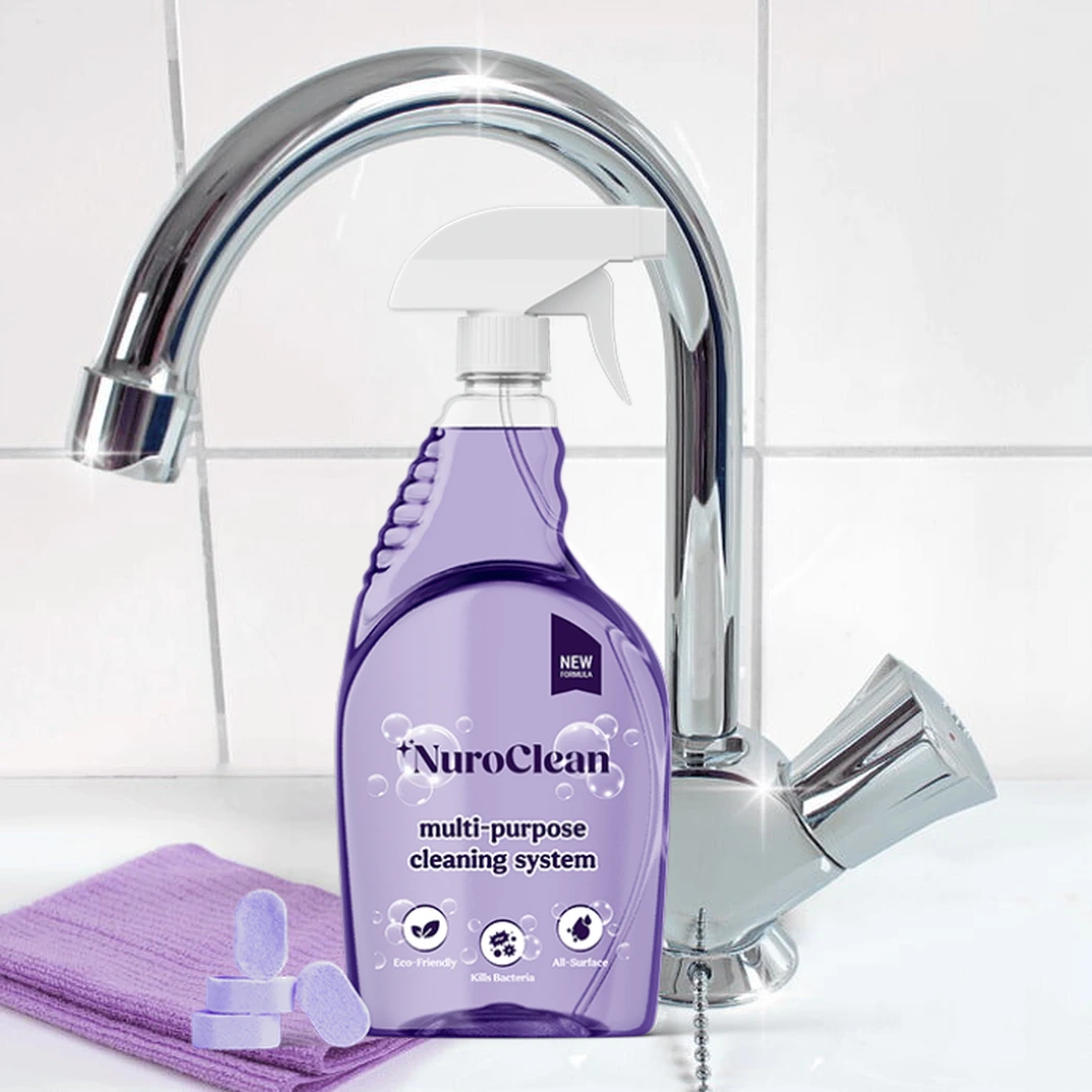 NuroClean clear spray bottle with purple accent trim and loose purple cleaning tablets standing on a clean kitchen counter in front of a chrome faucet